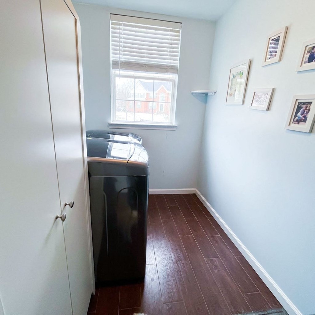 A kitchen with a black fridge and a window with blinds.