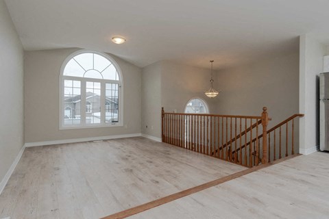 A room with a large arched window and wooden flooring.