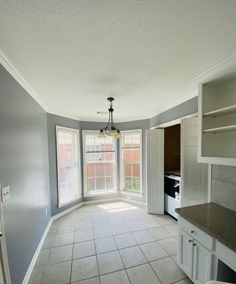 A kitchen with white cabinets and a grey floor.