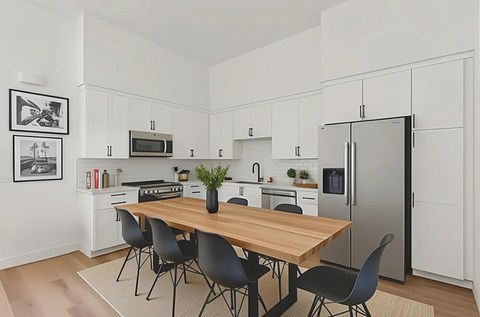 A modern kitchen with a wooden table and black chairs.