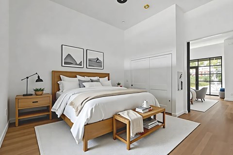 A bedroom with a large bed and a nightstand with a plant on it.