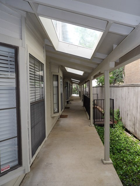 A long, narrow walkway with a skylight above and a fence on the right.