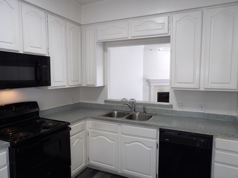 A kitchen with white cabinets and black appliances.