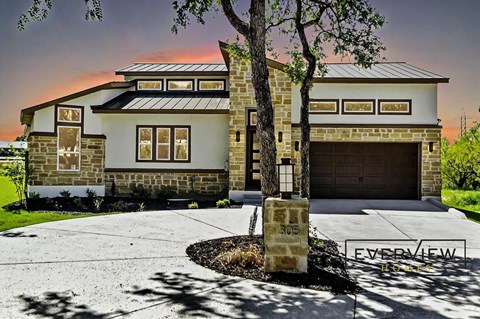 A house with a stone facade and a garage door is shown.