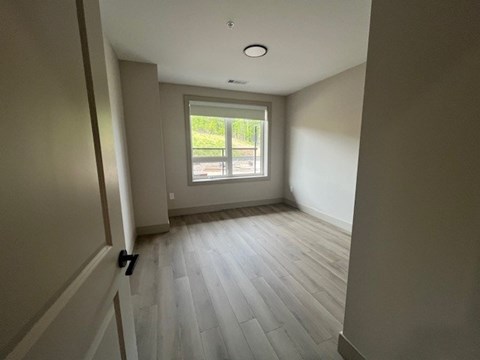 A room with a window and a wooden floor.