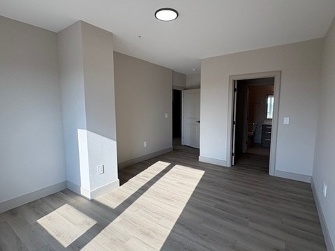 A room with a light on the ceiling and a doorway leading to another room.