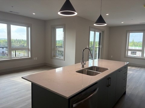 A kitchen with a large island and pendant lights.