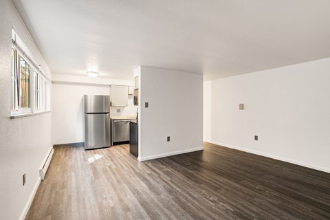 A kitchen area with a refrigerator, trash can, and a sink.