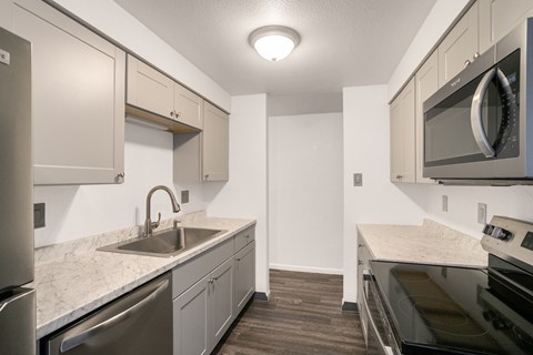 A kitchen with a sink, stove, and microwave.