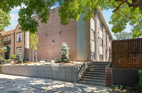 A modern building with a brick facade and a wooden fence.