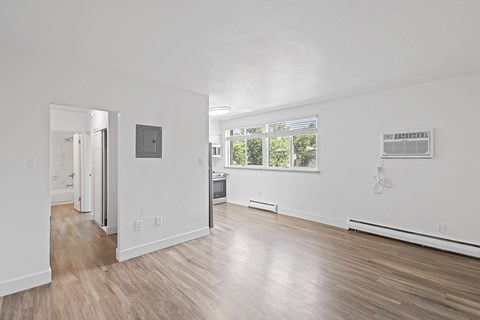 A white room with wood flooring and a window.