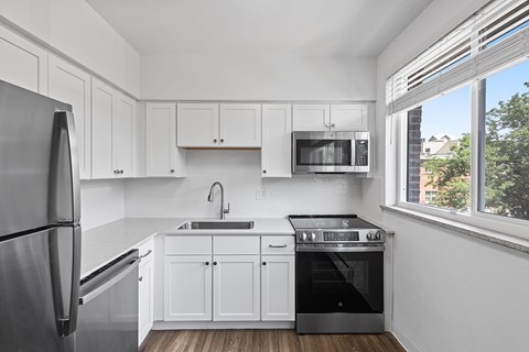 A modern kitchen with white cabinets and stainless steel appliances.