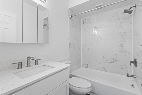 A white bathroom with a marble wall and a white toilet.