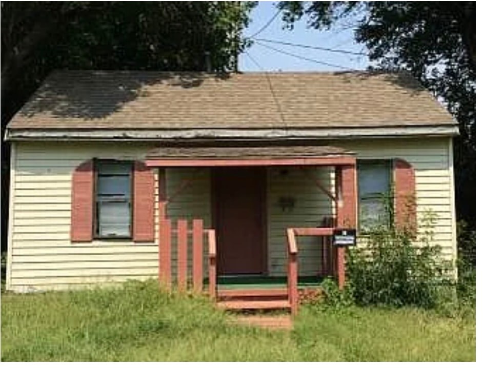 A small house with a red door and a porch.