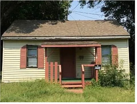 A small house with a red door and a porch.