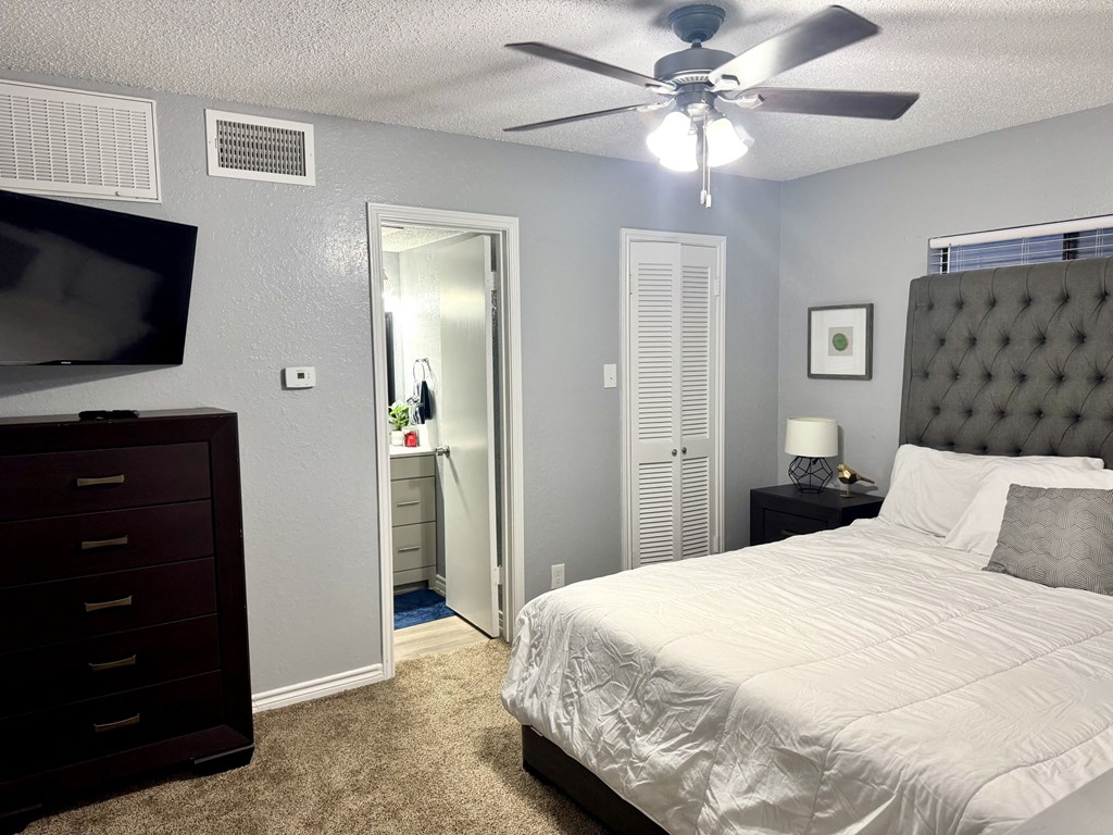 A bedroom with a bed, dresser, and a ceiling fan.