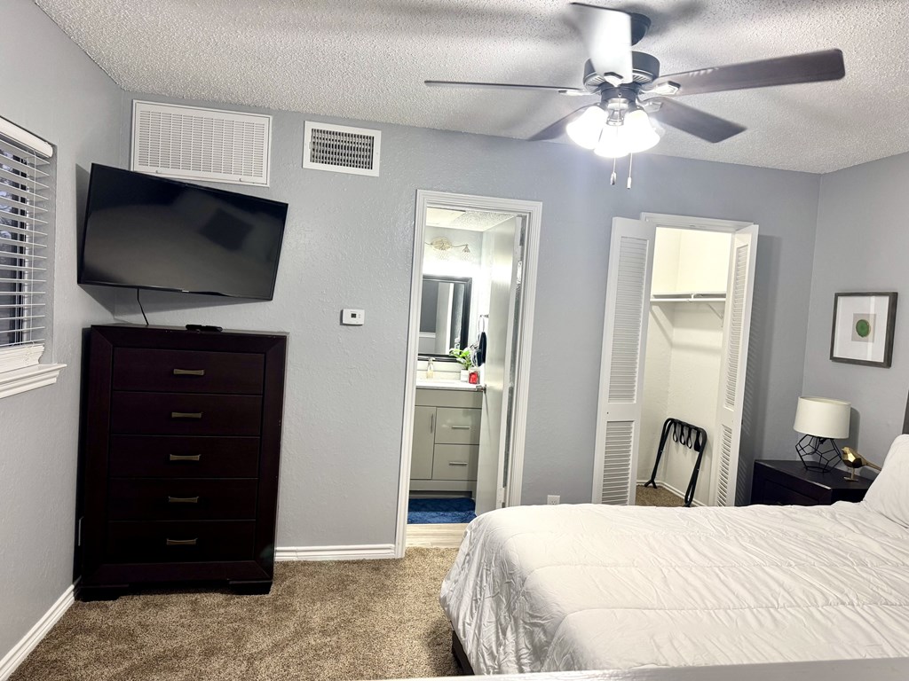A bedroom with a bed, dresser, and television.