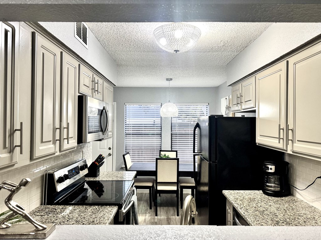 A kitchen with black appliances and granite countertops.