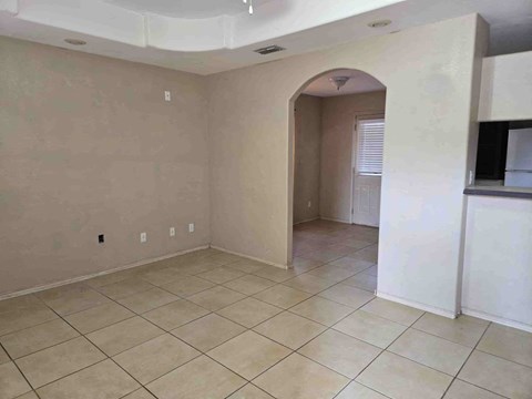 A spacious room with beige walls and tiled flooring.