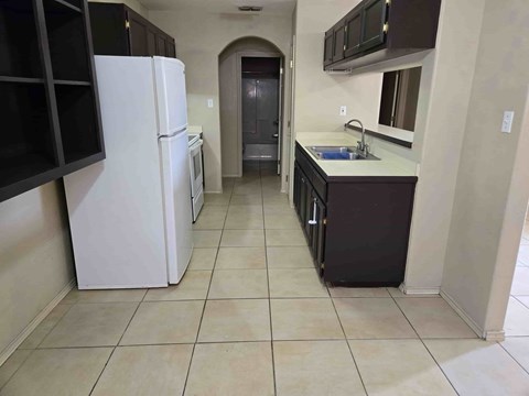 A kitchen with a white refrigerator and black cabinets.