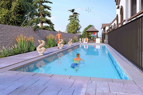 A person swims in a pool with a stone border and a metal fence.