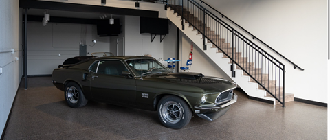 A green classic car is parked in a garage.