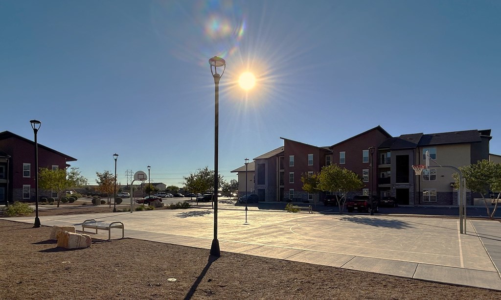 A basketball court is located in front of apartment buildings.