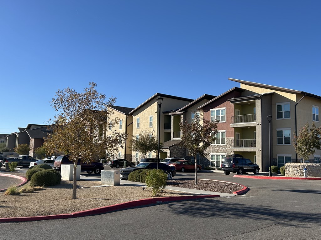 Apartment complex with a parking lot in front.