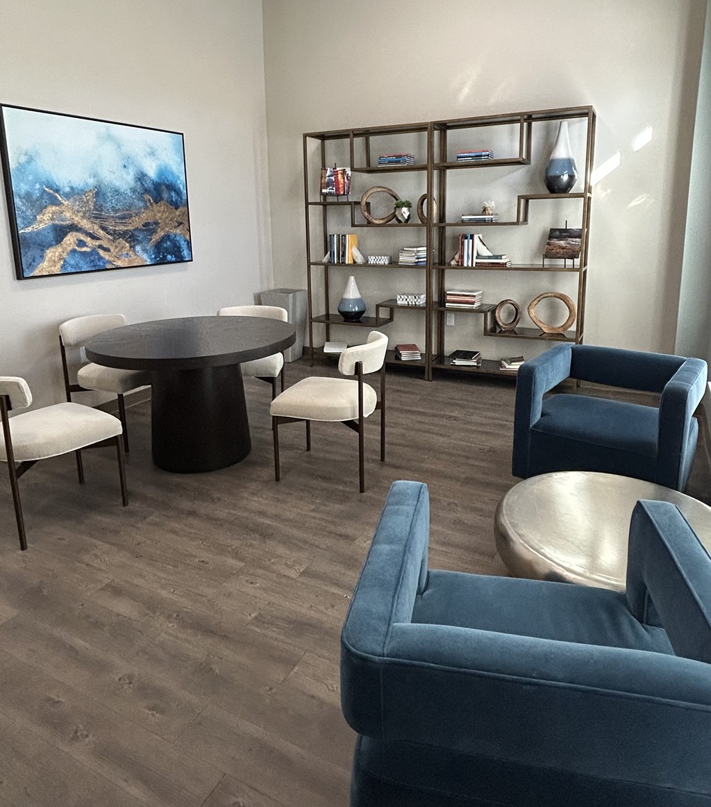 A living room with a grey sofa, a black table and a painting on the wall.