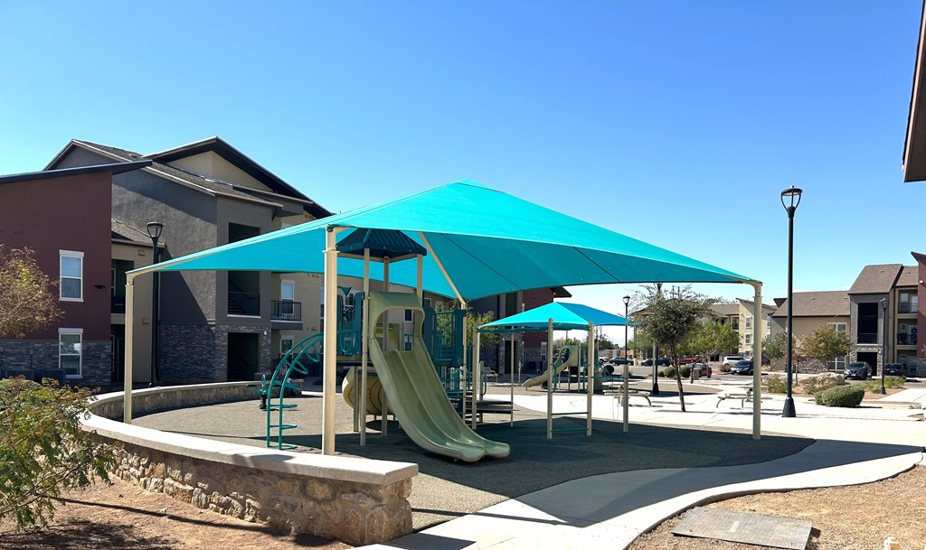 A playground with a blue canopy and a yellow slide.