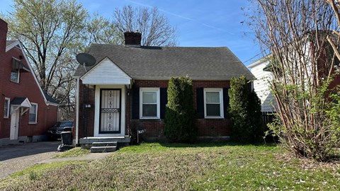 A small red brick house with a white door and windows.