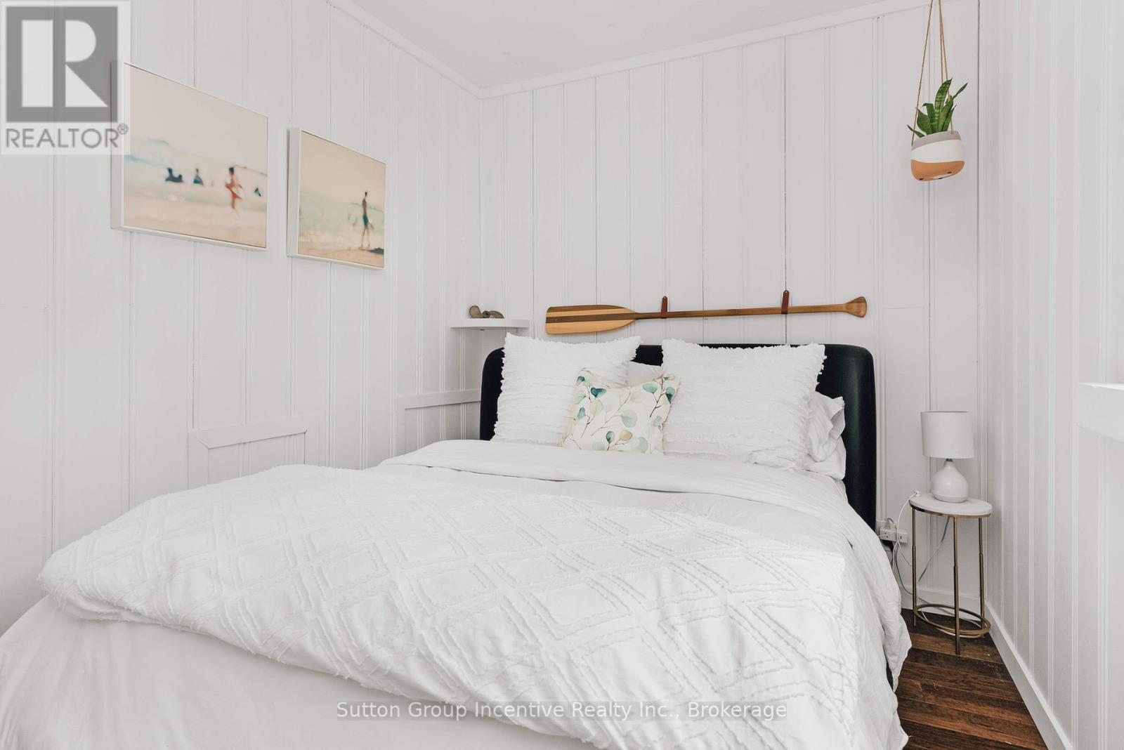 A bedroom with a white bed and a wooden headboard.
