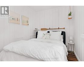 A bedroom with a white bed and a wooden headboard.