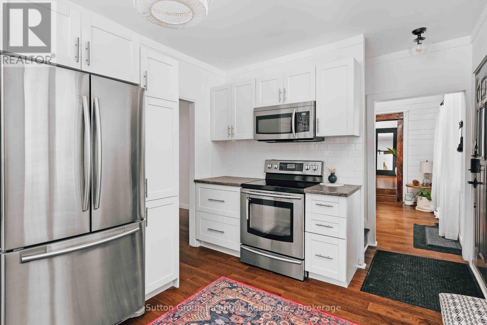 A kitchen with white cabinets and a stainless steel refrigerator.