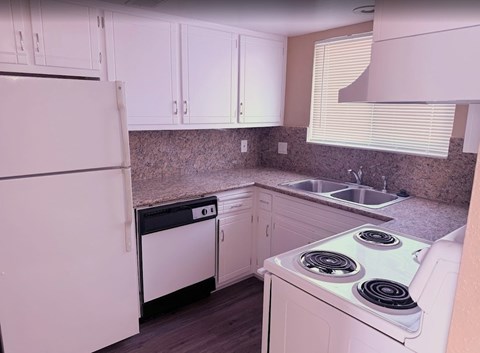 A white refrigerator is in a kitchen with white cabinets.