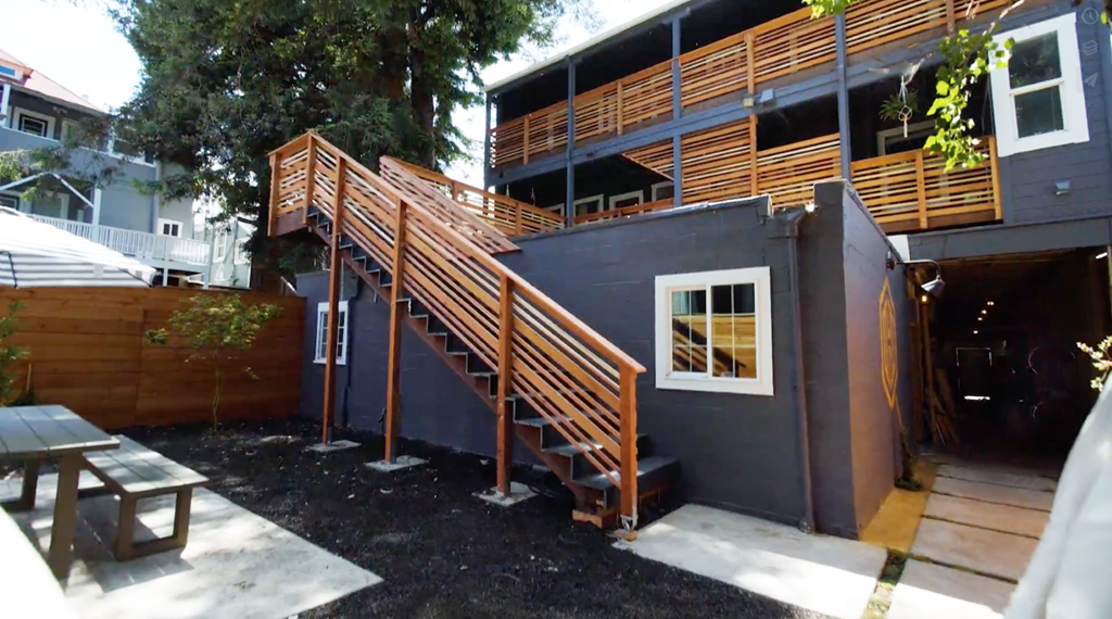 A wooden staircase leads to a balcony on the second floor of a modern house.