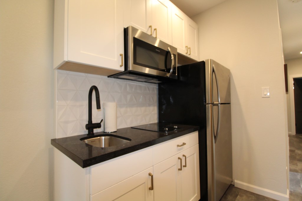 A kitchen with black countertops and white cabinets.