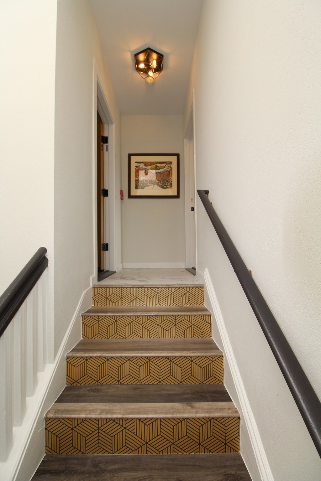 A staircase with a black railing and a brown and tan carpet.