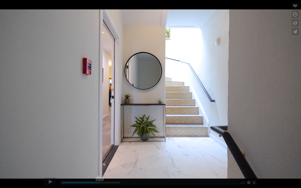 A hallway with a staircase and a mirror on the wall.