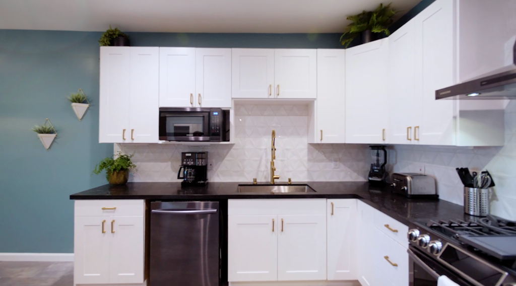 A kitchen with white cabinets and a black countertop.