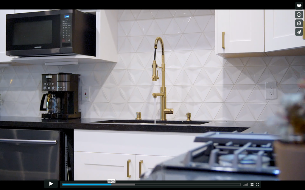 A kitchen with a black countertop and a gold faucet.