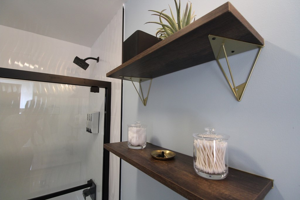 A shelf with a plant, candle, and glass container with straws.