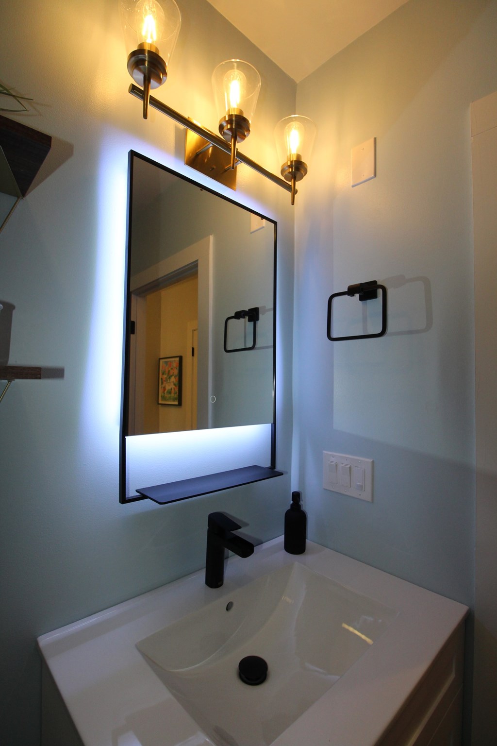 A bathroom with a sink, mirror and light fixture.