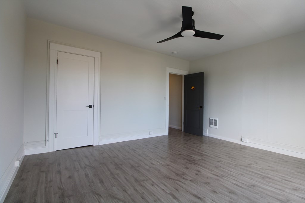 A room with a ceiling fan and wooden flooring.