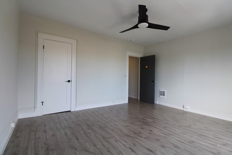A room with a ceiling fan and wooden flooring.