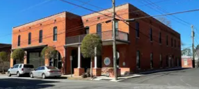 A red brick building with a white car parked in front.