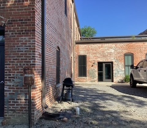 A white car is parked in front of a brick building.
