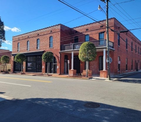 A red brick building with a black awning and a tree in front.