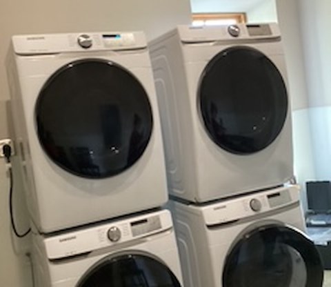 Three white front loading washing machines stacked on top of each other.