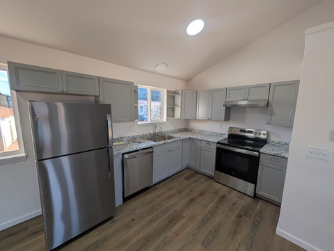 A kitchen with a stainless steel refrigerator and wooden flooring.